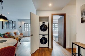 A modern apartment with a laundry room, a dining area with a table and chairs, and a living room with a sofa and a coffee table. - Modern 2BR Condo in Prime Montreal Location (Montreal)