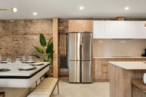 A modern kitchen with a brick wall, stainless steel refrigerator, and wooden cabinets. - Massive 9BR Luxury Stay • Plateau • sleep 22 (Montréal)