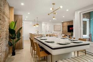 A modern dining area with a large island, wooden chairs, and a central chandelier. - Massive 9BR Luxury Stay • Plateau • sleep 22 (Montréal)