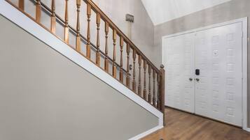 Una escalera con barandilla de madera que conduce a una puerta blanca con un ojo de cerradura.