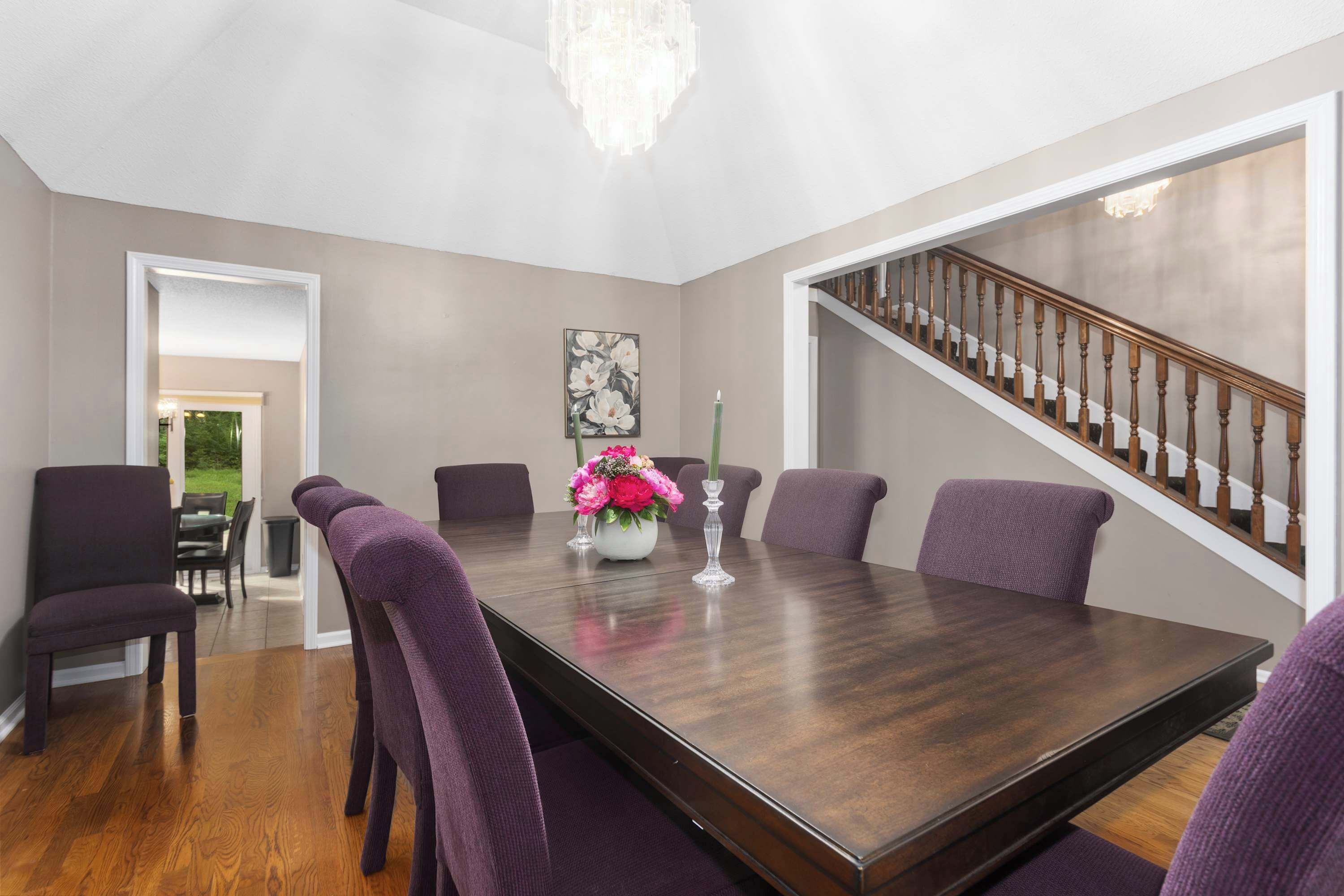 A dining room with a dark wood table, purple chairs, and a chandelier.