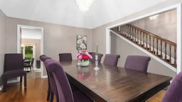 A dining room with a dark wood table, purple chairs, and a chandelier.