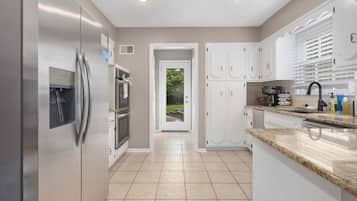 A modern kitchen with stainless steel appliances, white cabinetry, and a granite countertop.