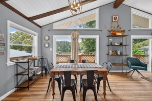 A dining area with a wooden table, chairs, and a view of the outdoors through large windows. - The Cove on Jackson Lake, Sleeps 9, Waterfront, Games, Hot tub + MORE! (Jackson)