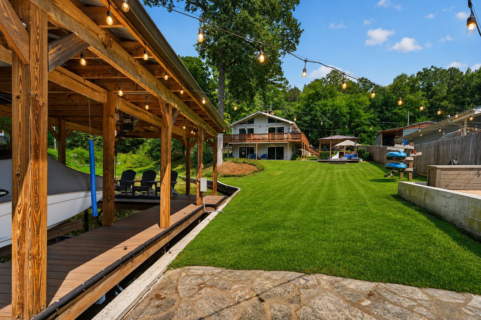 A wooden deck with outdoor seating, a grassy yard, and a house with a balcony.