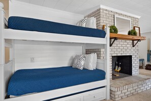 A bunk bed with blue bedding and a fireplace with decorative items.