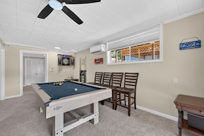 A pool table with chairs, a ceiling fan, and a dartboard in a room with beige walls and a window. - The Cove on Jackson Lake, Sleeps 9, Waterfront, Games, Hot tub + MORE! (Jackson)