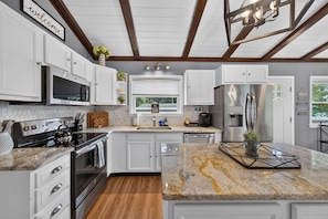 A modern kitchen with white cabinetry, stainless steel appliances, and a marble countertop. - The Cove on Jackson Lake, Sleeps 9, Waterfront, Games, Hot tub + MORE! (Jackson)
