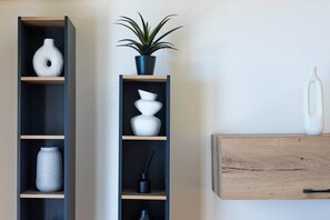 Two black shelving units with white and black vases, a potted plant, and a wooden cabinet with a handle. - S homes | Athens · Retro-Modern 2BR · Attiki Metro (Athens)