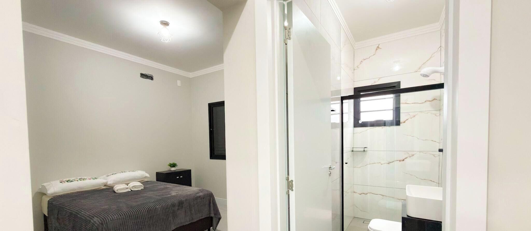 Ein Hotelzimmer mit einem Bett, einem kleinen Nachttisch, einem Spiegel und einer Duschkabine mit Glastür.