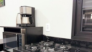 Una cucina con una macchina da caffè, un forno a microonde e un fornello a gas.