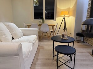 A modern living room with a white sofa, a round dining table, and a black floor lamp. - Country house, garden with trees, 4 km from Fougères (Romagné)