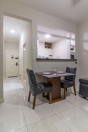 A dining area with a table, chairs, and a kitchen in the background. - 5 min from Copacabana Beach - B501 (Rio de Janeiro)