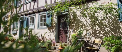 Ein traditionelles Fachwerkhäuschen mit Garten, einer Bank und einem Tisch.