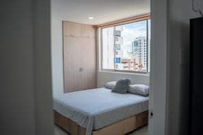 Una camera da letto con un letto, un armadio e una finestra che si affaccia sulla città.