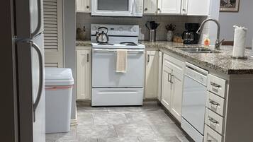 A kitchen with white cabinets, a microwave, stove, and a dishwasher.