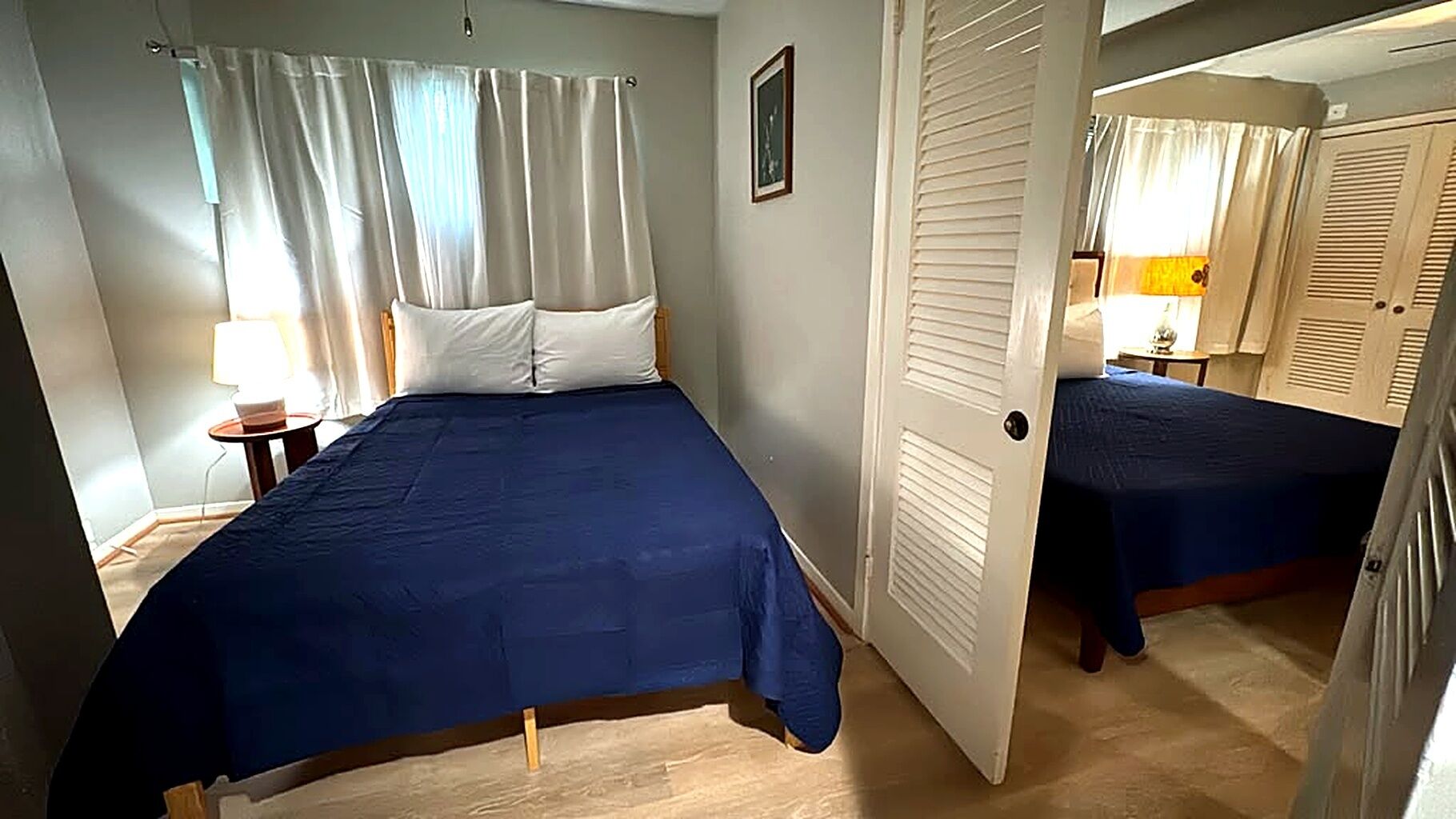 Une chambre à coucher avec un lit, une table de chevet, une lampe et une porte donnant sur une autre pièce.