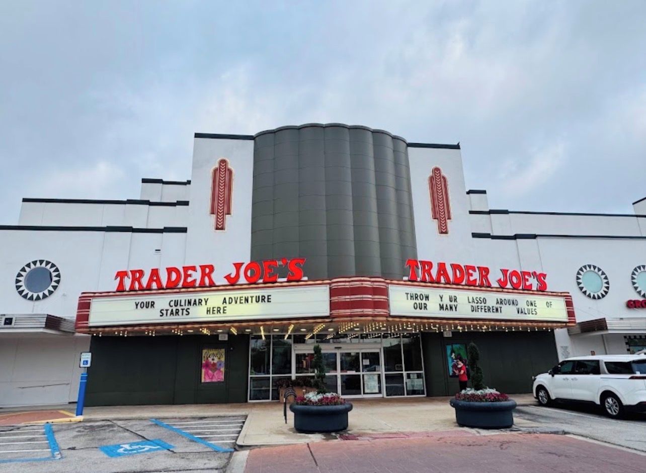 Un edificio con dos cines llamados 'Trader Joe's' con letreros que indican 'Aquí comienza tu aventura culinaria' y 'Lanza tu lazo alrededor de muchos valores diferentes'.