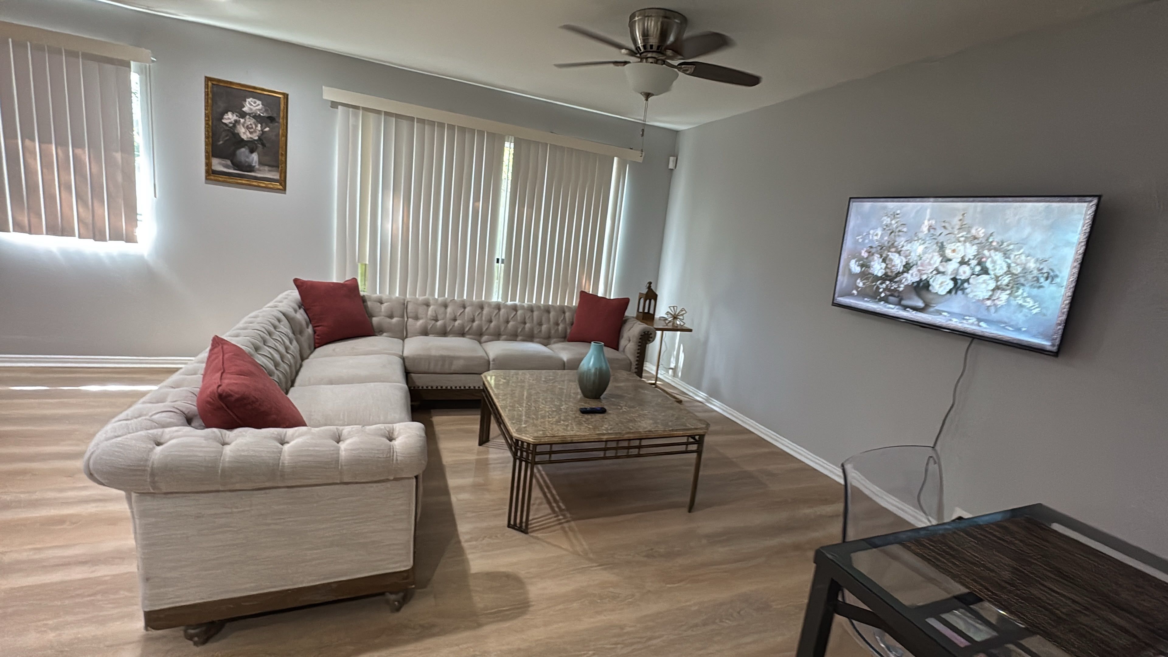 Una sala de estar con un sofá modular, una mesa de centro y un televisor montado en la pared.