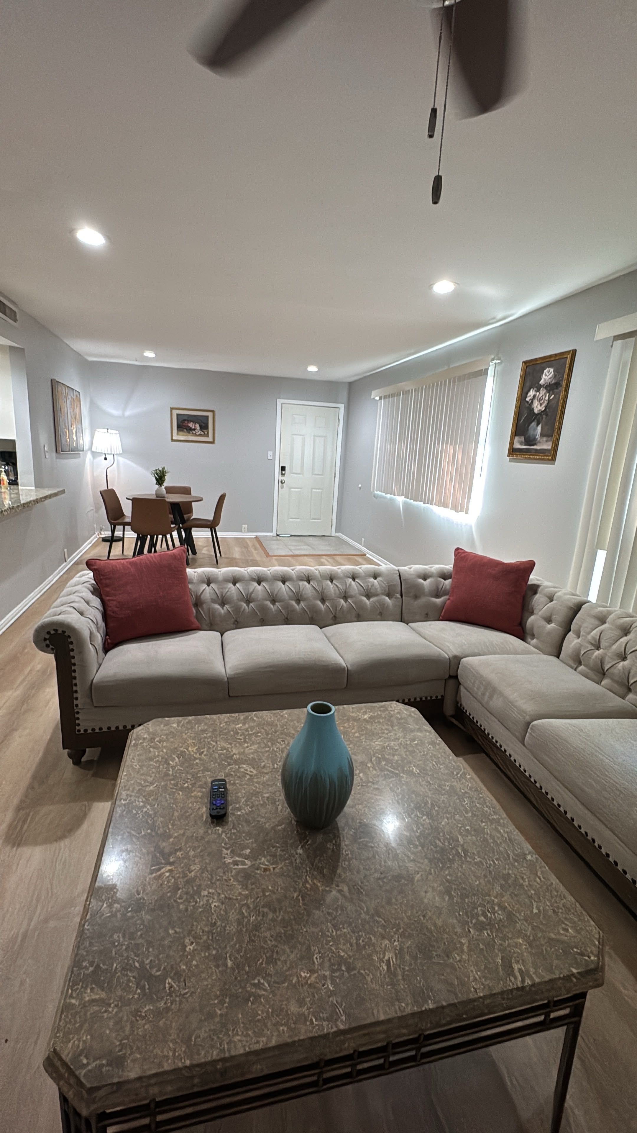 A living room with a sectional sofa, a coffee table, and a dining area in the background.