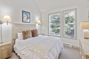 A bedroom with a large bed, two bedside lamps, a framed picture on the wall, and a window with blinds. - Ski In/Out Sunset Luxury: Etta Place Too 115 at the base of Lift 7 (Telluride)