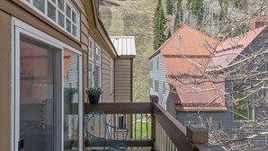 A balcony with a chair and a potted plant, overlooking a mountainous landscape. - Ski In/Out Sunset Luxury: Etta Place Too 115 at the base of Lift 7 (Telluride)
