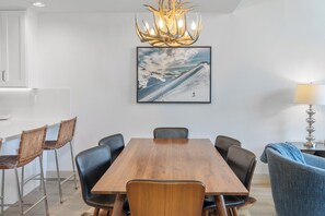 Uma sala de jantar com mesa de madeira, cadeiras pretas, um candelabro e um quadro na parede.