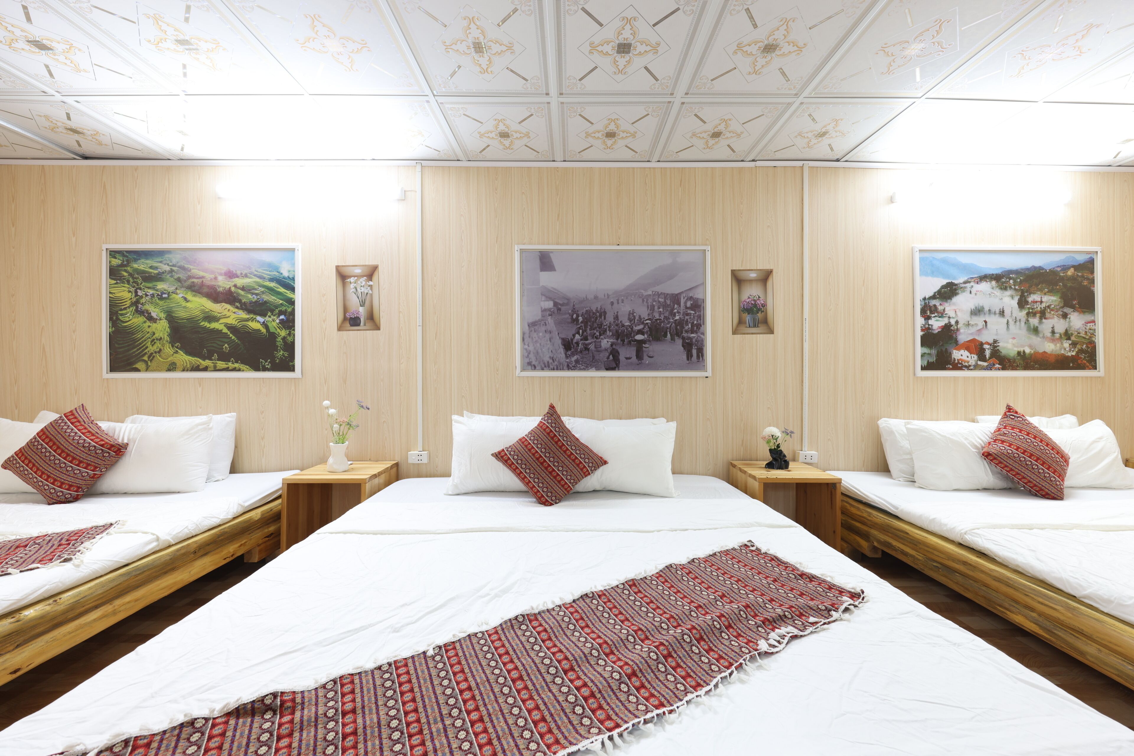 A hotel room with two beds, a large window, and three framed pictures on the wall.