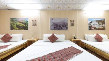 A hotel room with two beds, a large window, and three framed pictures on the wall.
