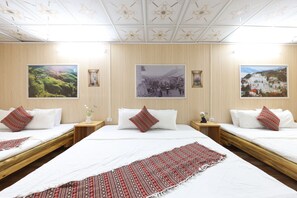 A hotel room with two beds, a large window, and three framed pictures on the wall.