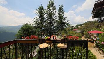 A terrace with two chairs and a table, overlooking a mountainous landscape with a view of the valley below.