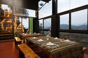 Un comedor con una mesa dispuesta para cuatro, ventanas amplias con vistas a la montaña y una escalera con barandilla.