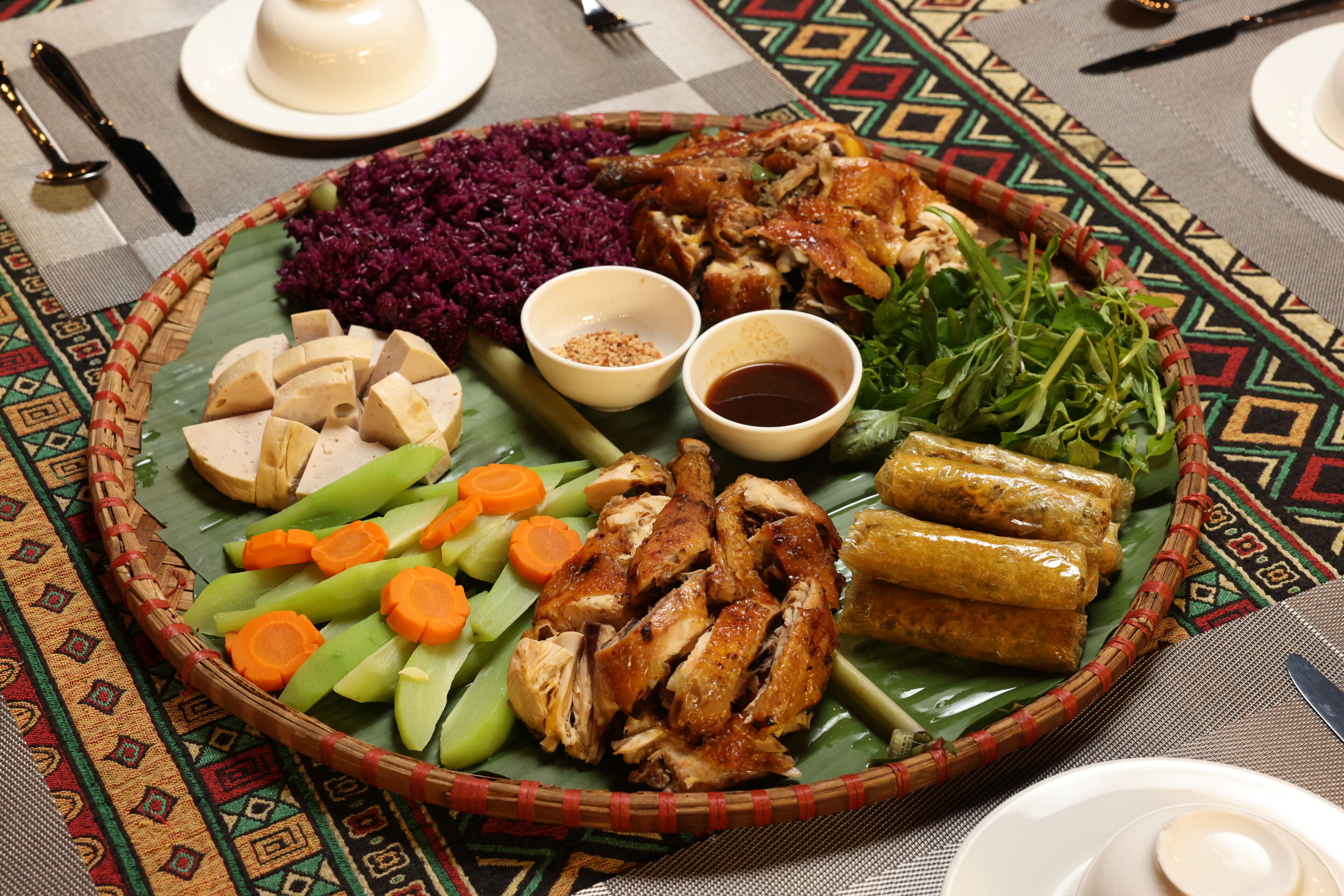 A traditional meal with various dishes including rice, meat, and vegetables on a woven plate.