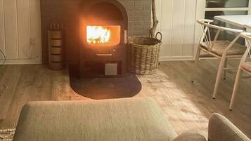 A cozy living room with a fireplace, a wicker basket, and a dining area with a table and chairs.