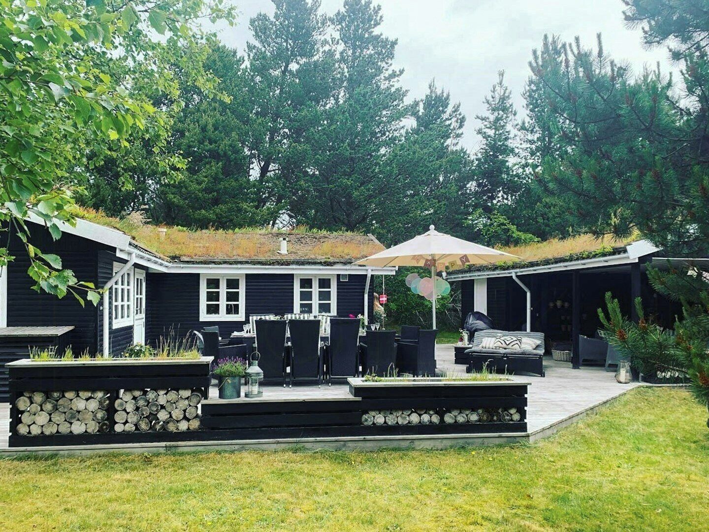 Una casa con un patio cubierto, mobiliario exterior y un paraguas grande.