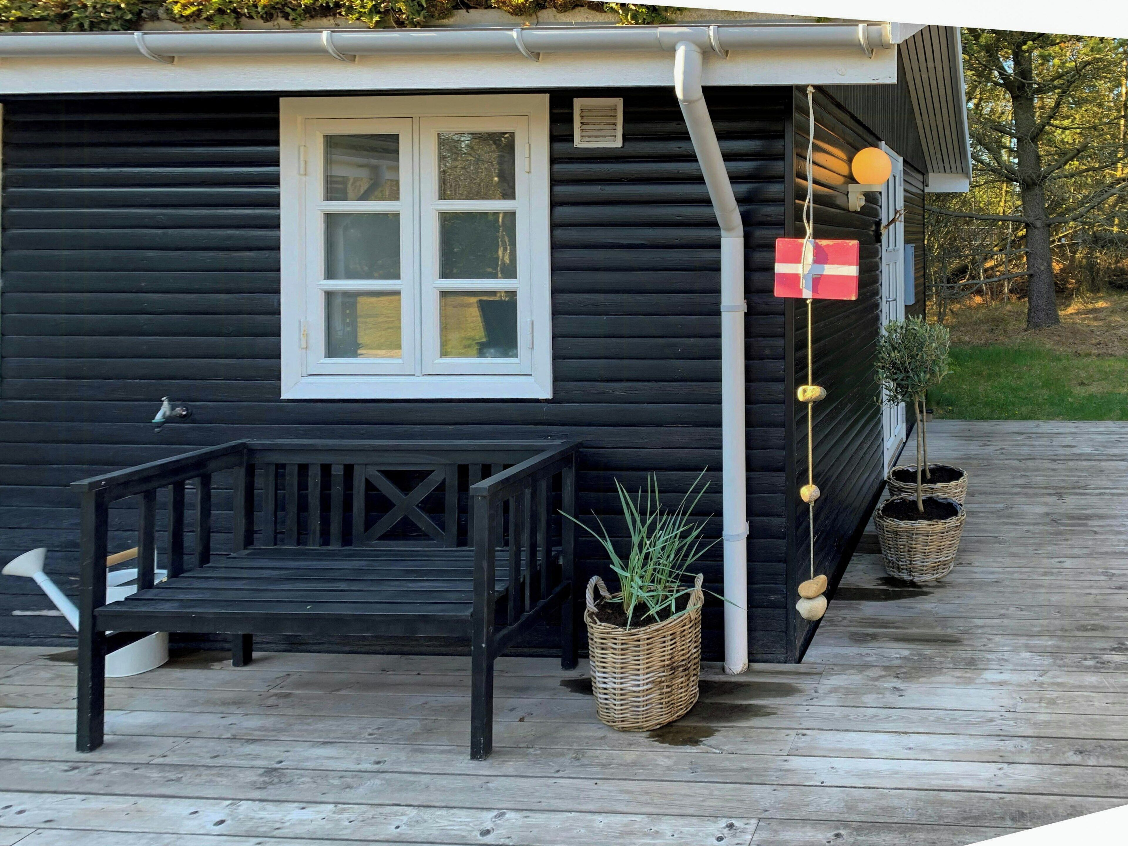 Eine Holzhütte mit Veranda, einem Fenster und zwei Blumentöpfen.