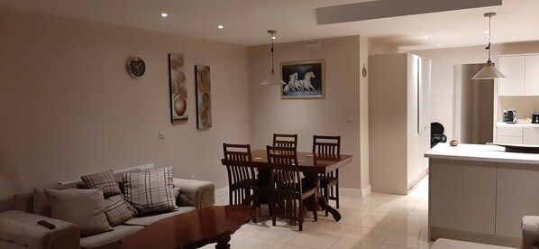Ein modernes Wohnzimmer mit einer Couch, einem Esstisch mit Stühlen und einer Küchenzeile mit Arbeitsplatte und Schränken.