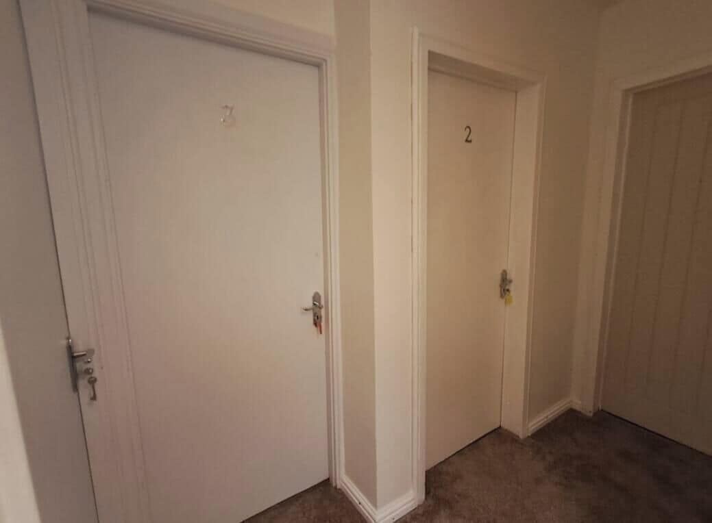 Un corridoio con due porte chiuse, una delle quali porta il numero 2.