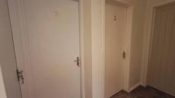 Un corridoio con due porte chiuse, una delle quali porta il numero 2.