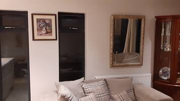 A living room with a sofa, a cabinet with glass doors, and two framed pictures on the wall.