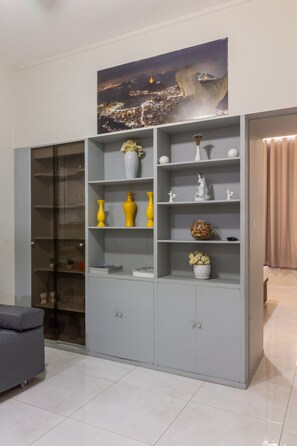 A grey, multi-shelf cabinet with various decorative items and a cityscape painting above it. - 5 min From Copacabana Beach - B501 (Rio de Janeiro)