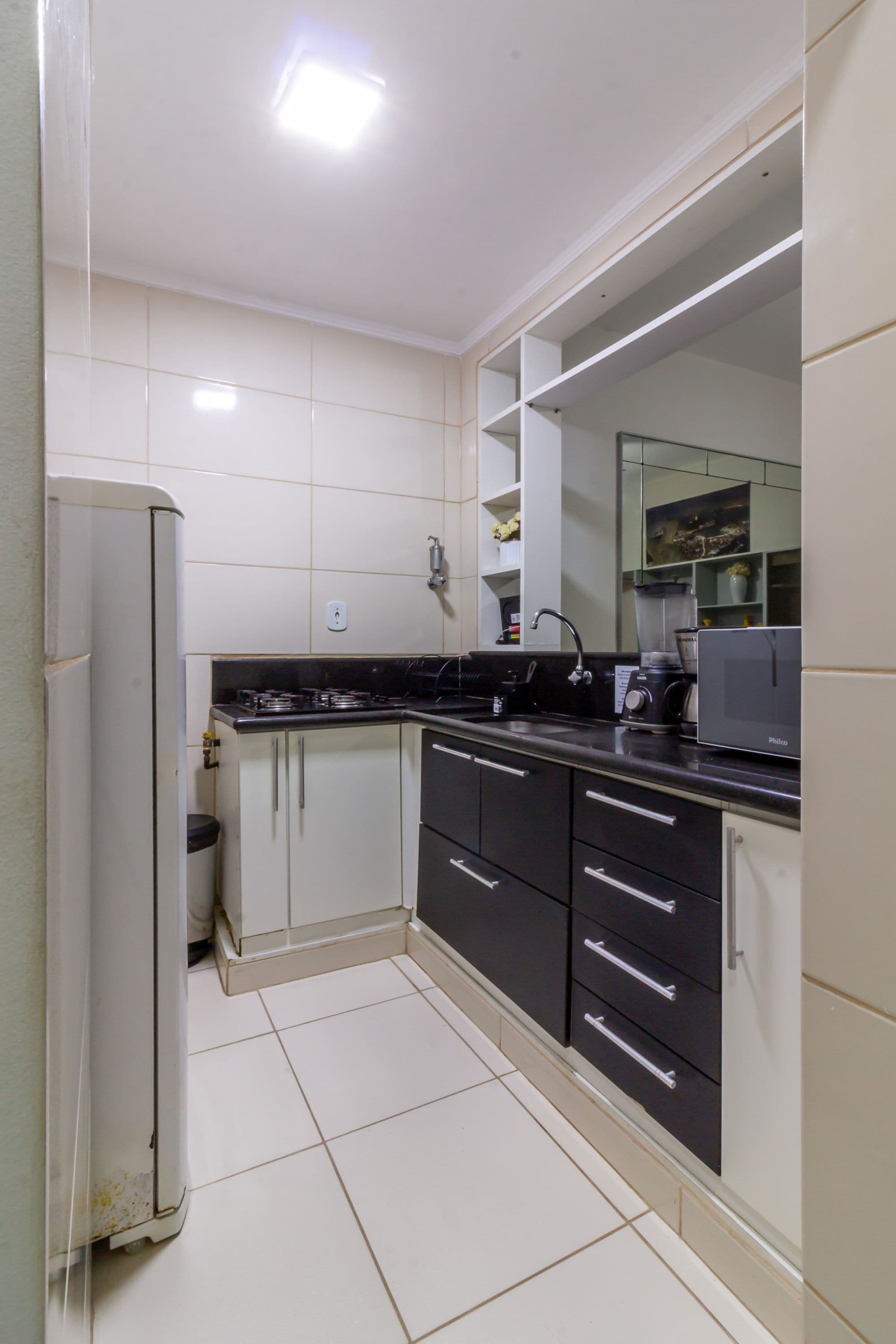 A compact kitchen with white cabinets, a black countertop, and a built-in microwave.