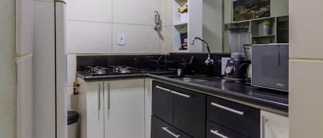 A compact kitchen with white cabinets, a black countertop, and a built-in microwave.