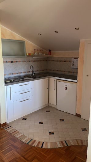 Eine Küche mit weißen Schränken, einer Edelstahl-Spüle und einer gefliesten Spritzschutzwand.