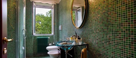 Un baño con un lavamanos de vidrio, un inodoro y una ducha.