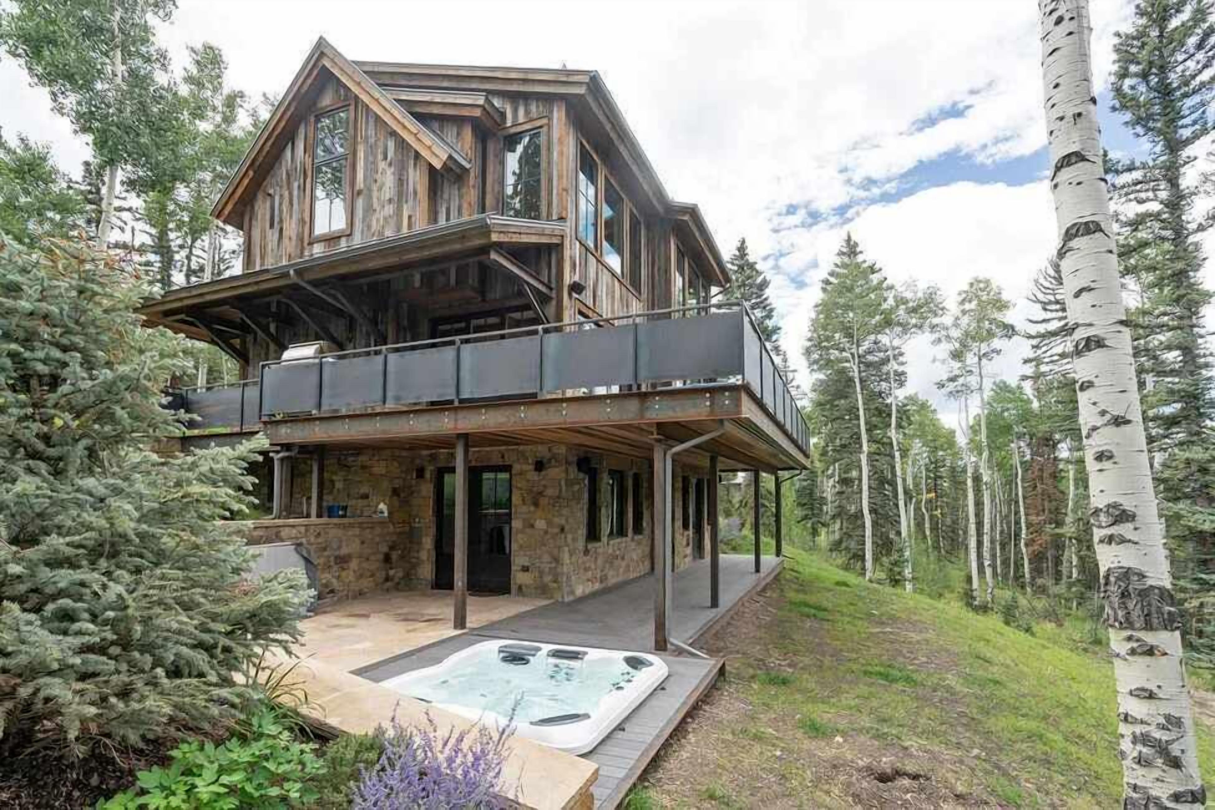 Une cabane en bois à deux étages avec un jacuzzi à l’avant.