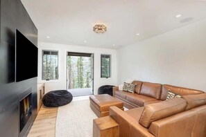 Ein modernes Wohnzimmer mit einer Ledersofa, einem Flachbildfernseher und einem Kamin.