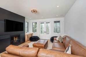 Ein modernes Wohnzimmer mit Kamin, Ledersofa und Flachbildfernseher.