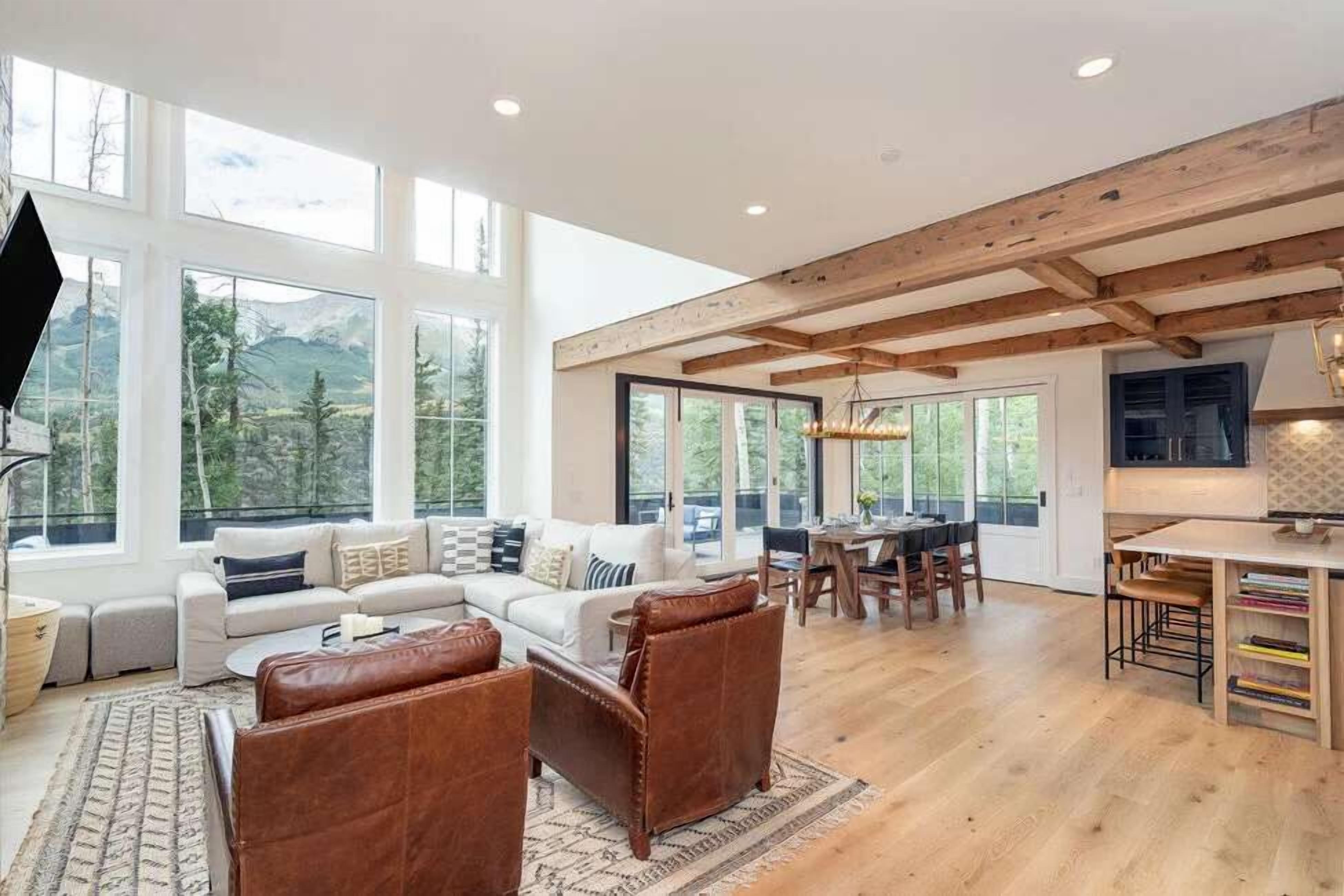 A spacious living area with a large window, a dining area, and a kitchen.