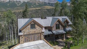 A two-story house with a stone facade, a garage, and a view of mountains. - Luxe Telluride Oasis - Hot Tub & Deck & Views (Mountain Village)